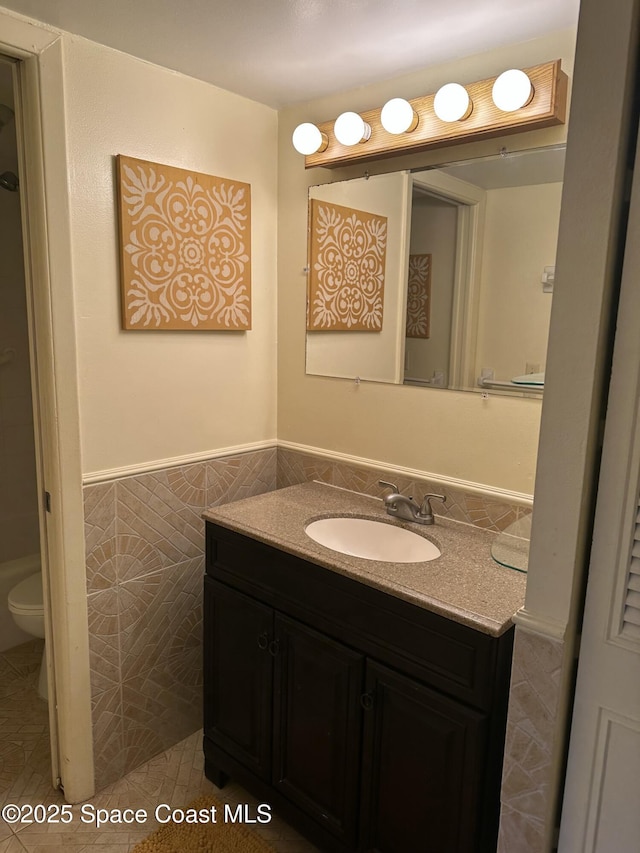 bathroom with tile walls, vanity, tile patterned flooring, and toilet