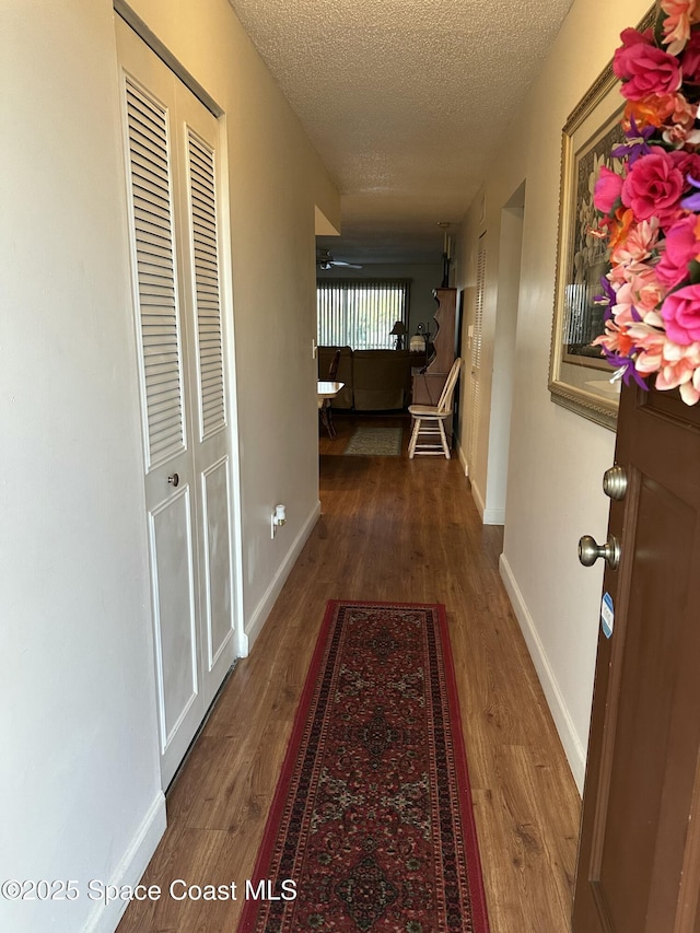 hall with dark hardwood / wood-style flooring and a textured ceiling