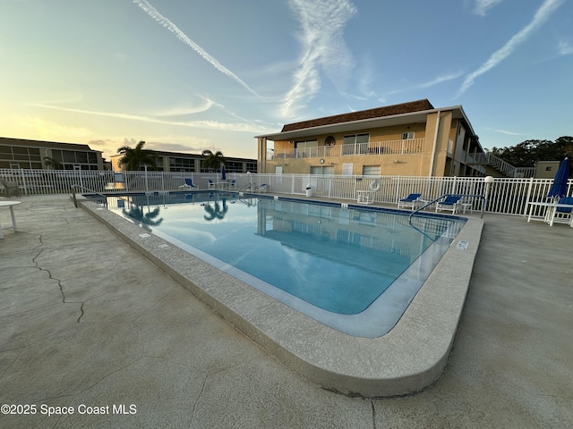 pool at dusk featuring a patio