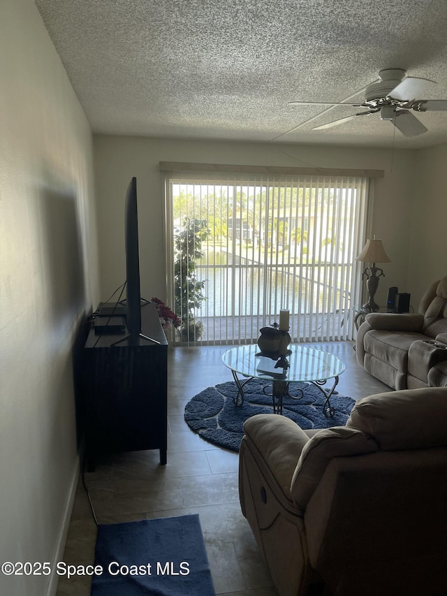 living room with ceiling fan and a textured ceiling