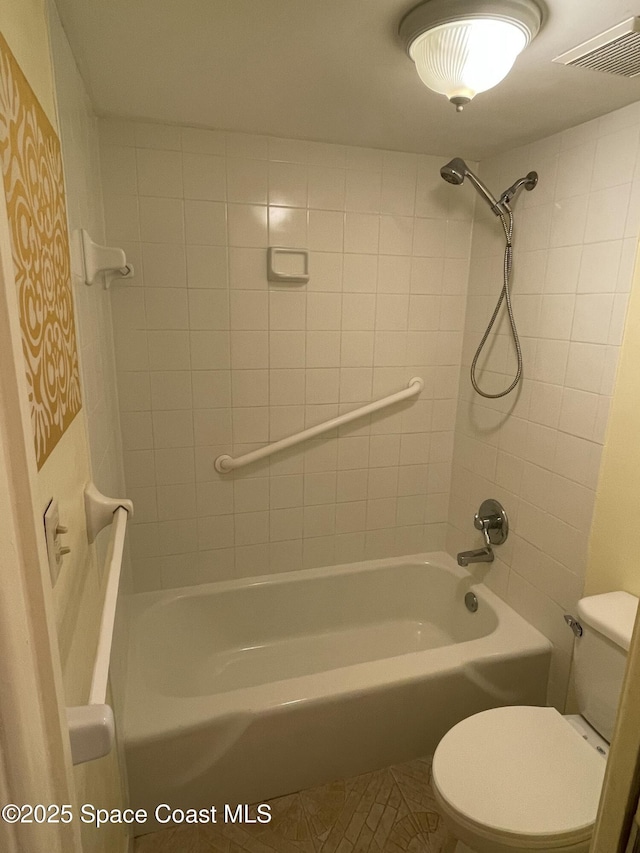 bathroom featuring tiled shower / bath combo, tile patterned floors, and toilet