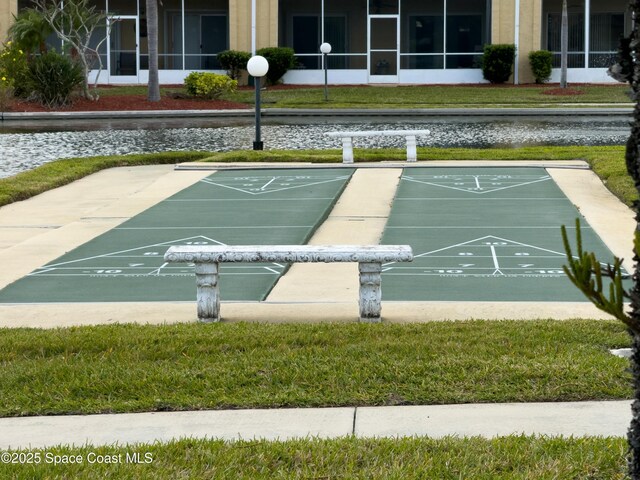 view of community with a water view, shuffleboard, and a lawn