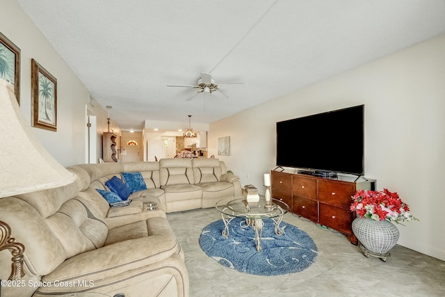 living area featuring ceiling fan with notable chandelier and a textured ceiling
