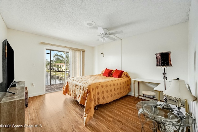 bedroom featuring baseboards, a textured ceiling, access to outside, and wood finished floors