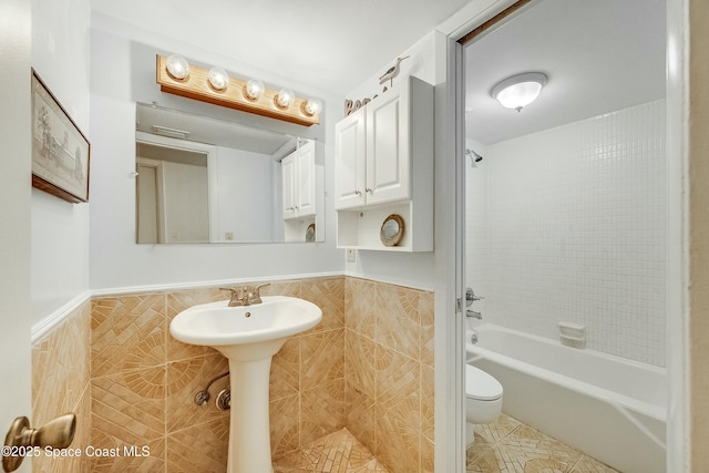full bathroom featuring a wainscoted wall, toilet, and tile walls