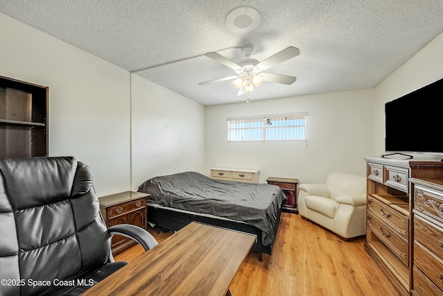 bedroom featuring light wood-style flooring, a textured ceiling, and ceiling fan