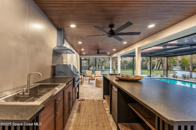 view of patio featuring sink, ceiling fan, glass enclosure, a grill, and exterior kitchen