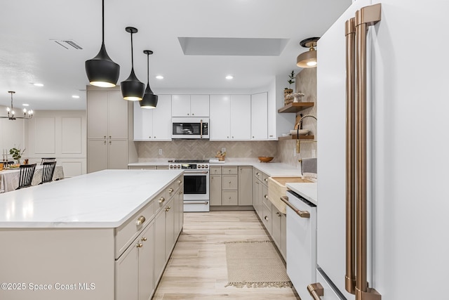 kitchen with pendant lighting, white cabinets, backsplash, high end appliances, and a center island