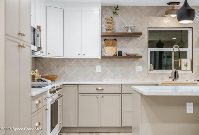 kitchen with white cabinetry, high end white range, sink, and tasteful backsplash