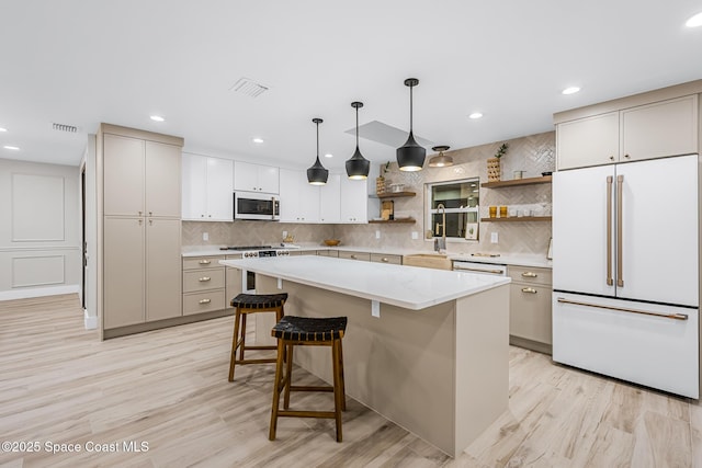 kitchen featuring a kitchen island, pendant lighting, white appliances, decorative backsplash, and white cabinets