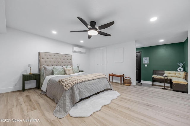 bedroom with light hardwood / wood-style floors, an AC wall unit, and ceiling fan