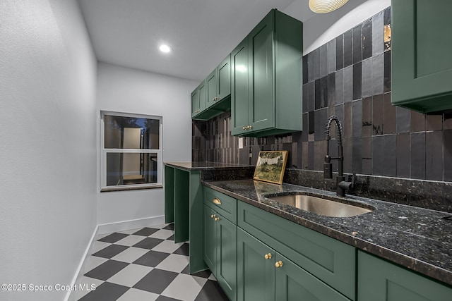 kitchen featuring tasteful backsplash, dark stone counters, sink, and green cabinets