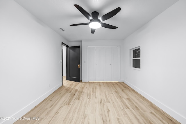 unfurnished bedroom featuring ceiling fan, light hardwood / wood-style floors, and a closet