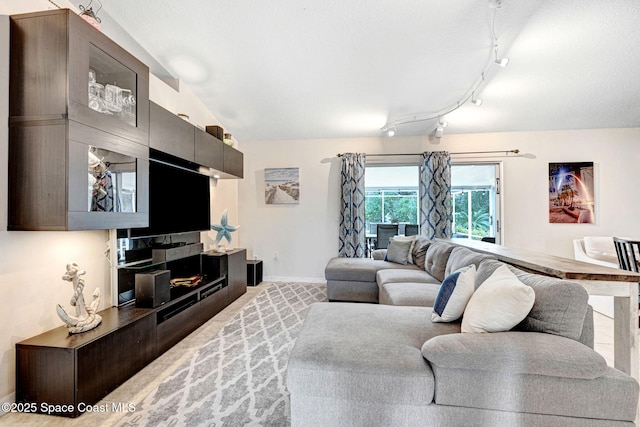 carpeted living room with vaulted ceiling and rail lighting