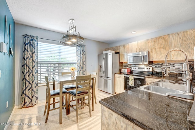 kitchen featuring sink, appliances with stainless steel finishes, decorative backsplash, a textured ceiling, and decorative light fixtures