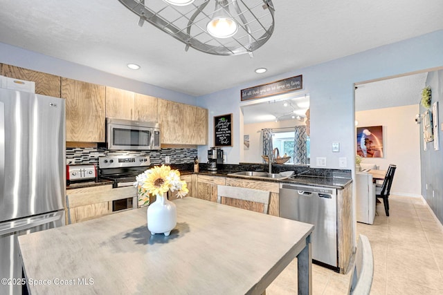 kitchen featuring sink, light tile patterned floors, kitchen peninsula, stainless steel appliances, and backsplash