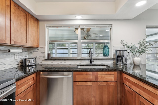 kitchen with sink, ceiling fan, backsplash, stainless steel appliances, and dark stone counters