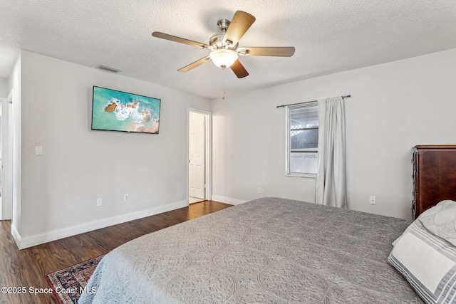 bedroom featuring ceiling fan, dark hardwood / wood-style floors, and a textured ceiling