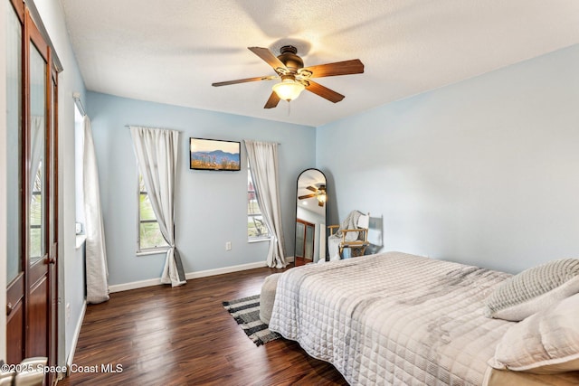 bedroom with ceiling fan, a textured ceiling, and dark hardwood / wood-style flooring