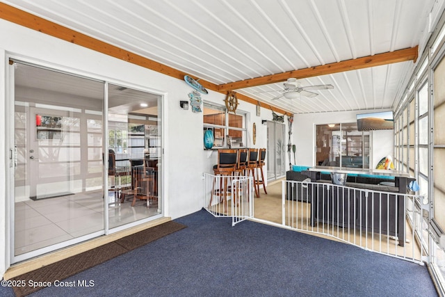 sunroom featuring beam ceiling and ceiling fan