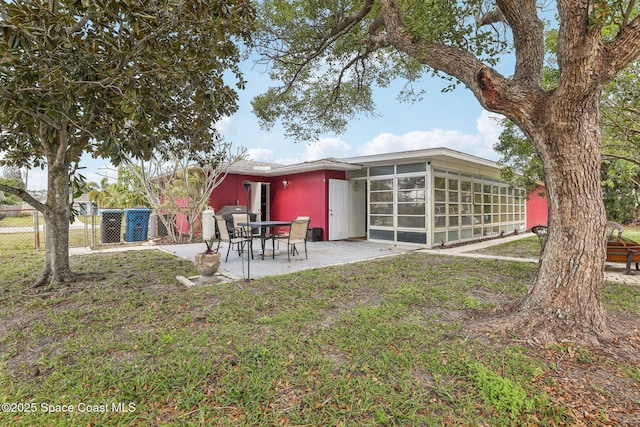 back of house with a patio area, a sunroom, and a lawn