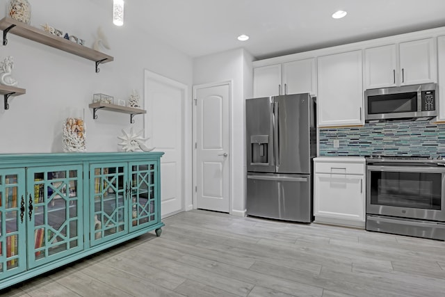 kitchen featuring white cabinetry, appliances with stainless steel finishes, light hardwood / wood-style floors, and backsplash