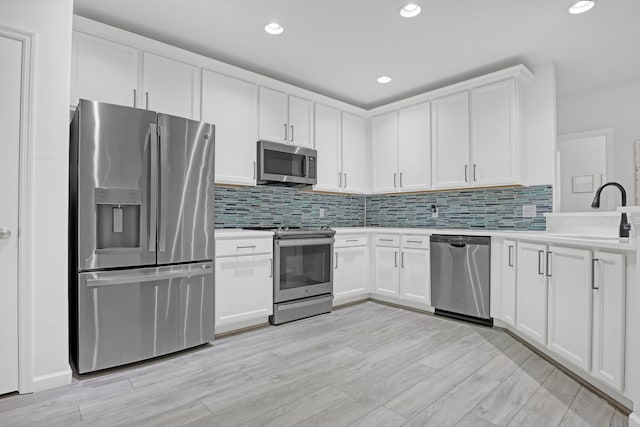 kitchen featuring tasteful backsplash, sink, white cabinets, and appliances with stainless steel finishes