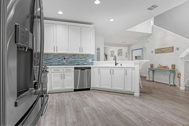 kitchen featuring white cabinetry, stainless steel appliances, kitchen peninsula, and sink