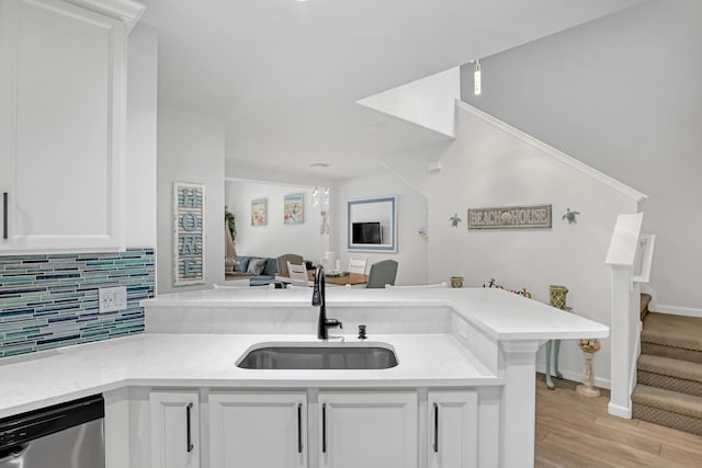 kitchen featuring white cabinetry, dishwasher, sink, backsplash, and kitchen peninsula