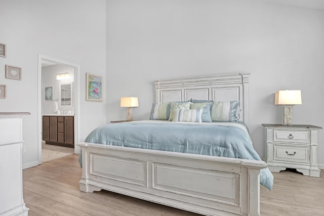 bedroom featuring connected bathroom and light wood-type flooring