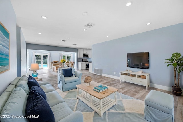 living room with french doors and light wood-type flooring