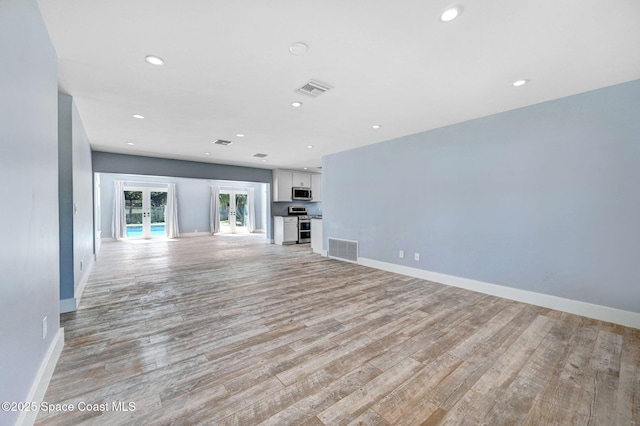 unfurnished living room featuring french doors and light hardwood / wood-style flooring