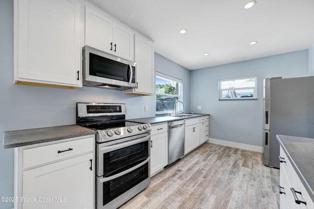 kitchen featuring white cabinetry, appliances with stainless steel finishes, sink, and light wood-type flooring