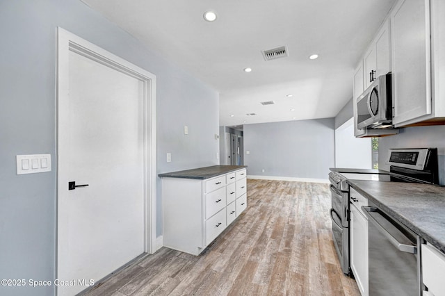 kitchen with stainless steel appliances, white cabinetry, and light hardwood / wood-style flooring