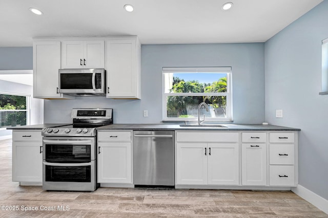 kitchen with stainless steel appliances, white cabinetry, sink, and a wealth of natural light