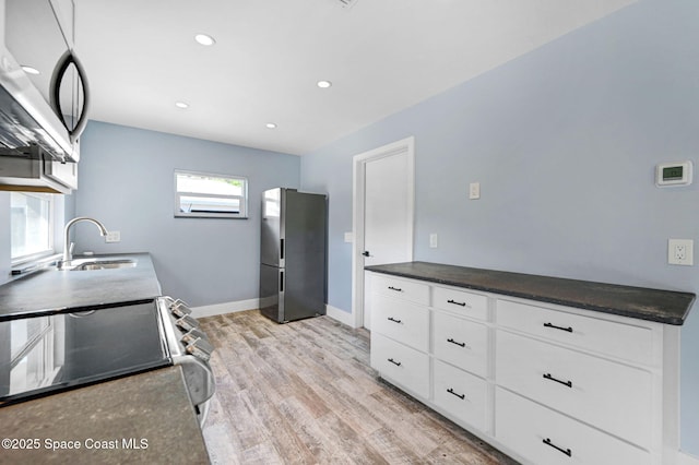 kitchen with white cabinetry, appliances with stainless steel finishes, sink, and light hardwood / wood-style flooring