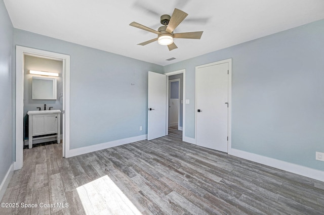 unfurnished bedroom featuring ceiling fan, ensuite bathroom, and hardwood / wood-style floors