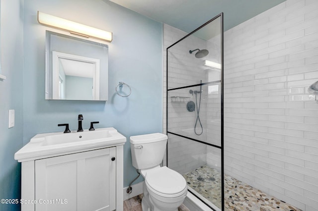 bathroom featuring tiled shower, vanity, and toilet