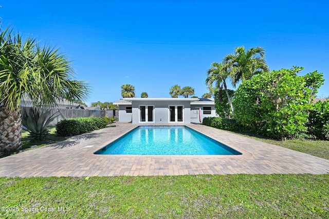 view of pool with a patio, a lawn, and french doors