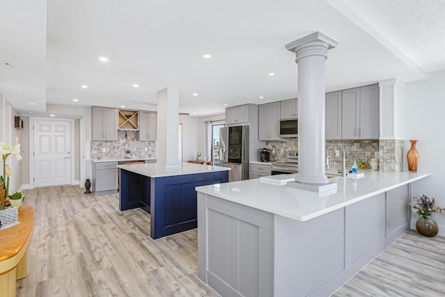 kitchen with ornate columns, gray cabinetry, a center island, kitchen peninsula, and stainless steel appliances