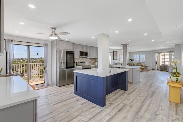 kitchen with gray cabinets, appliances with stainless steel finishes, decorative columns, and kitchen peninsula