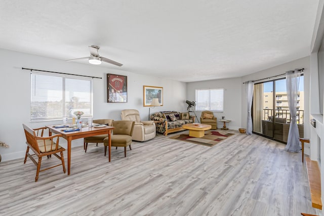 living room with a textured ceiling, light hardwood / wood-style flooring, and ceiling fan