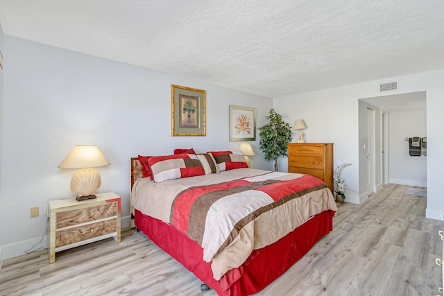 bedroom with light hardwood / wood-style floors and a textured ceiling