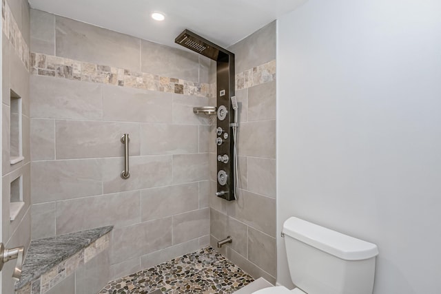 bathroom with tiled shower and toilet