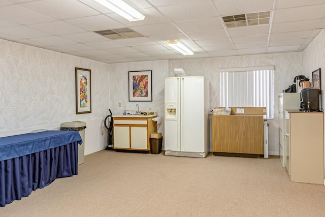 carpeted bedroom featuring sink, a paneled ceiling, and white fridge with ice dispenser