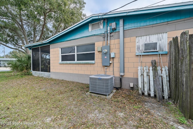 view of home's exterior featuring a sunroom, central AC unit, and a lawn