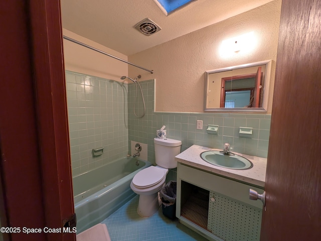 full bathroom with toilet, tiled shower / bath, tile walls, a textured ceiling, and tile patterned flooring