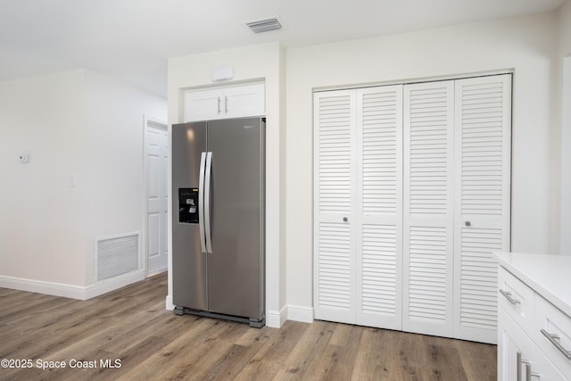 kitchen featuring white cabinetry, light wood-type flooring, and stainless steel refrigerator with ice dispenser