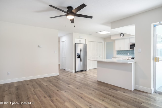 kitchen with white cabinetry, appliances with stainless steel finishes, tasteful backsplash, and light hardwood / wood-style flooring