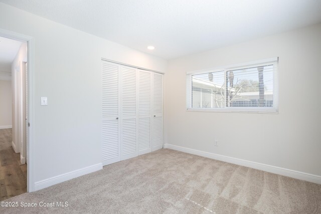 unfurnished bedroom with a closet and light carpet